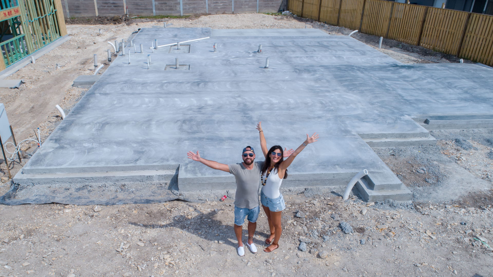 Happy couple standing in front of home foundation