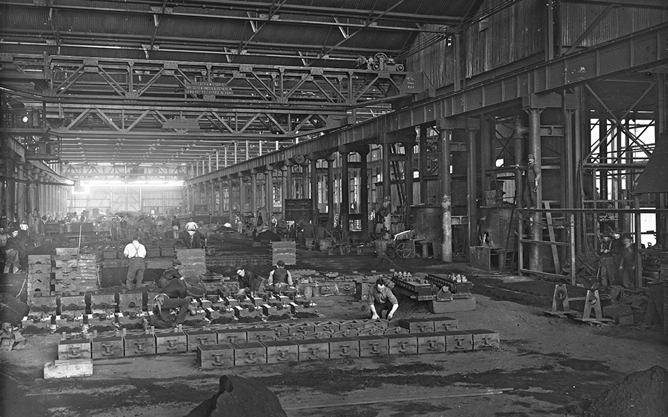 Sand casting in the foundry. Moulds were made by pressing foundry patterns into sand-packed mould boxes, which were then filled with molten metal to form the casting. 