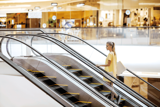 Woman going up escalator in shopping mall